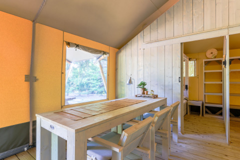 Interior view of a glamping safari tent with wooden furniture at Recreatiepark de Paalberg, Netherlands.