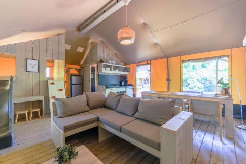Interior de una tienda glamping safari con salón, cocina y comedor en Recreatiepark de Paalberg, Países Bajos.