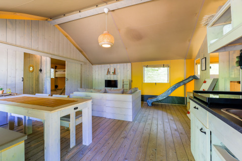Innenansicht eines Glamping-Zeltes im Recreatiepark de Paalberg, Niederlande, mit Rutsche und Sofa.