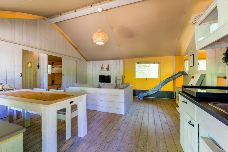 Innenansicht eines Glamping-Zeltes im Recreatiepark de Paalberg, Niederlande, mit Rutsche und Sofa.