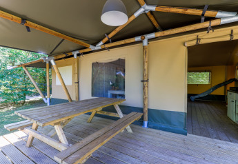Udendørs træbord og bænk på en terrasse ved Glamping Tent på Recreatiepark de Paalberg, Holland.