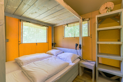Interior view of a cozy bedroom in the Glamping Tent at Recreatiepark de Paalberg, Netherlands.