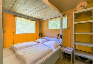 Interior view of a cozy bedroom in the Glamping Tent at Recreatiepark de Paalberg, Netherlands.
