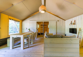 Intérieur d’une tente glamping spacieuse au Recreatiepark de Paalberg, Pays-Bas, avec décor en bois clair.