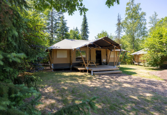 Safari-Glampingzelt im Recreatiepark de Paalberg in den Niederlanden, umgeben von Bäumen im Grünen.