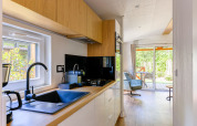 Moderne compacte keuken en zithoek in Heide Lodge, Recreatiepark de Paalberg, Nederland, met zicht op de tuin.