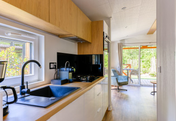 Moderne tiny house keuken en zithoek in Heide Lodge op Recreatiepark de Paalberg, Nederland, met tuinzicht.