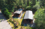 Vista aérea de dos tiny houses en Heide Lodge, Recreatiepark de Paalberg, Países Bajos, rodeados de árboles.