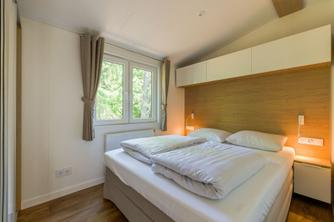 Dormitorio luminoso en Heide Lodge de Recreatiepark de Paalberg, Países Bajos, con cama doble cómoda.