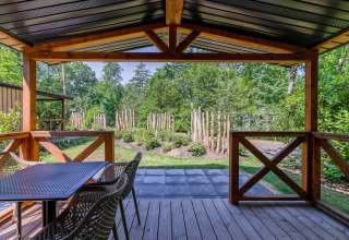 Vista desde la terraza de madera en Heide Lodge, Recreatiepark de Paalberg, con jardín y bosque.