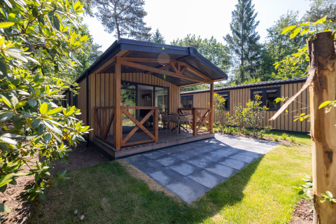 Acogedora tiny house Heide Lodge en Recreatiepark de Paalberg, Países Bajos, con terraza y jardín alrededor.