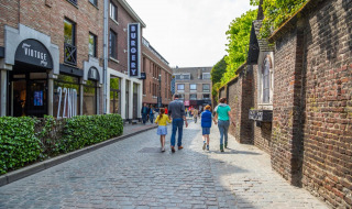 Eine Familie spaziert auf einer Kopfsteinpflasterstraße in einem Ferienpark mit Glamping-Unterkünften.
