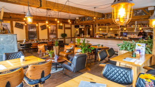 Gemütliche Lounge im Ferienpark mit Glamping, warmem Licht, Holzmöbeln, Bar und grünen Pflanzen.