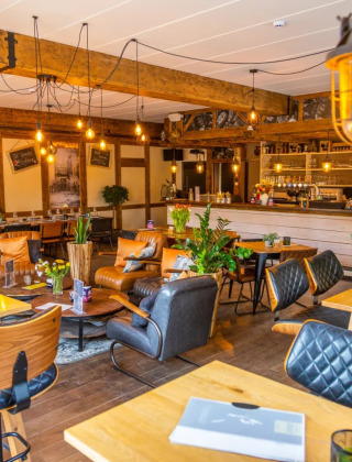 Acogedora cafetería en parque de vacaciones glamping con muebles de madera, plantas y luz cálida.