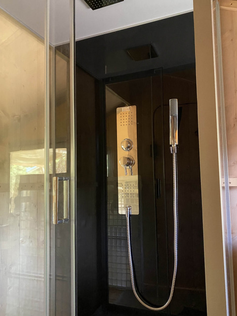 Moderne douche in een glamping tent op Tolne Camping in Denemarken met glazen deur en handdouche.