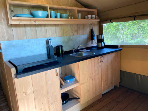 Kitchen area inside a glamping tent with wooden cabinets, sink, and coffee maker at Tolne Camping, Denmark.