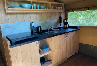 Keukenruimte in glamping tent met houten kasten, spoelbak en koffiezet bij Tolne Camping, Denemarken.