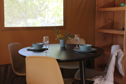Eettafel in een glampingtent bij Tolne Camping in Denemarken, gedekt met servies, glazen en bloemen.