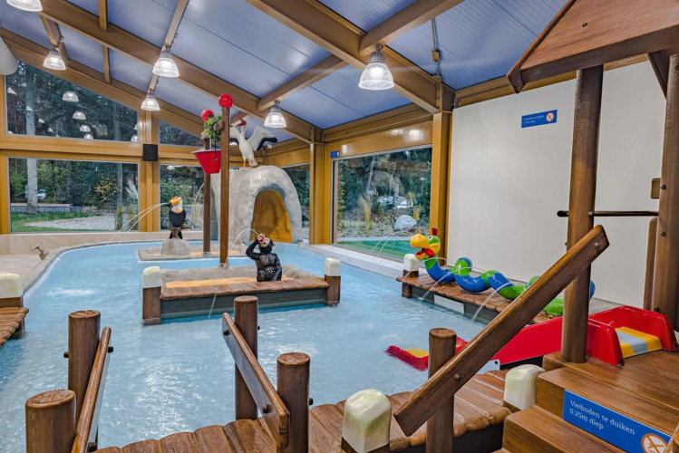 Area giochi coperta con piscina per bambini e giochi d'acqua in un villaggio vacanze con glamping.