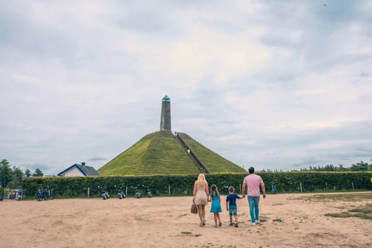 Famiglia si avvicina a una collina piramidale con torre in un villaggio vacanze che offre glamping.