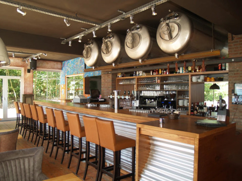 Bar moderno con tanques de cerveza y taburetes altos en un parque vacacional, ideal para glamping.
