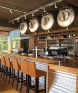 Bar moderno con tanques de cerveza y taburetes altos en un parque vacacional, ideal para glamping.