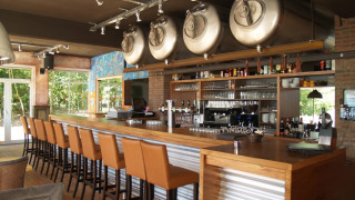 Bar moderno con tanques de cerveza y taburetes altos en un parque vacacional, ideal para glamping.