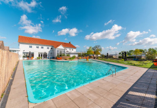 Udendørs swimmingpool med liggestole ved et feriehus på en feriepark, perfekt til glamping og afslapning.