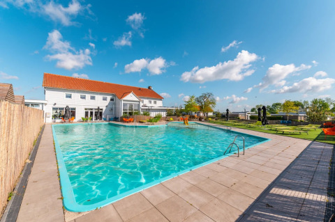 Piscina al aire libre con tumbonas cerca de una casa de vacaciones en un parque que ofrece glamping y relax.