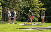 Gruppe voksne og børn spiller minigolf på en solrig dag ved Recreatiepark de Paalberg i Gelderland.