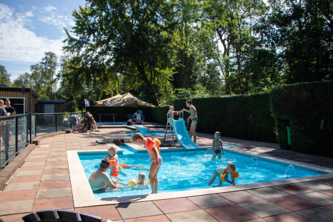 Kinder spielen im Schwimmbecken mit Rutsche im Recreatiepark de Paalberg, Gelderland, Niederlande.