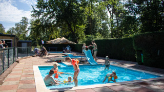 Niños juegan en piscina con tobogán en Recreatiepark de Paalberg, Gelderland, Países Bajos.