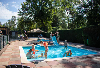 Niños juegan en piscina con tobogán en Recreatiepark de Paalberg, Gelderland, Países Bajos.