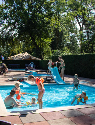 Niños juegan en piscina con tobogán en Recreatiepark de Paalberg, Gelderland, Países Bajos.