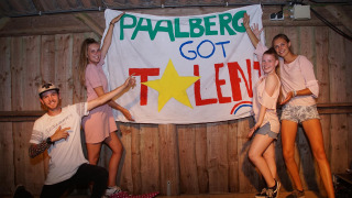 Grupo de jóvenes posando frente a un cartel de 'Paalberg Got Talent' en un parque de vacaciones en Gelderland, Países Bajos.
