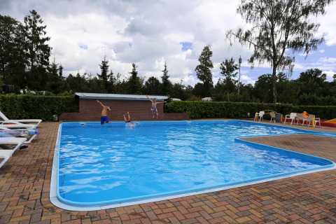 Bambini che saltano nella piscina all'aperto a Camping de Meibeek, un parco vacanze in Gelderland, Paesi Bassi.