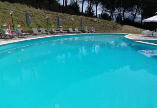 Udendørs swimmingpool ved Casa & Glamping Sorriso med liggestole og parasoller i Umbria, Italien.
