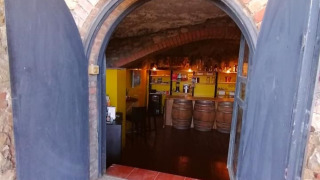 Puerta arqueada abre paso a una bodega-bar con barriles en Casa & Glamping Sorriso, Umbría, Italia.