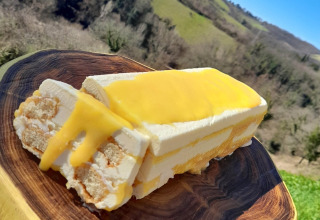 A slice of dessert with lemon cream on a wooden board, hills in the background at Umbria, Italy.
