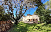 Solrigt billede af et hus og blomstrende træer ved Casa & Glamping Sorriso, feriepark i Umbrien, Italien.