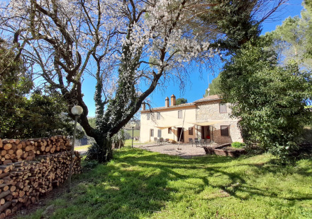 Zonnige foto van Casa & Glamping Sorriso, vakantiepark in Umbrië, Italië, met bloeiende bomen en tuin.