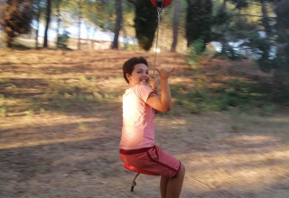 Child smiling and riding a zipline outdoors at Casa & Glamping Sorriso holiday park in Umbria, Italy.