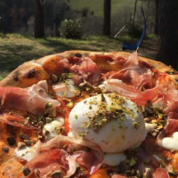 Foto al aire libre de una pizza con burrata, jamón y pistachos en Baschi, Umbría, Italia.