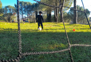 Een kind speelt voetbal op het grasveld van Casa & Glamping Sorriso, omgeven door bomen in Umbrië, Italië.