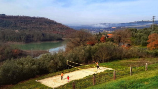 Personas juegan voleibol en una cancha de arena rodeada de naturaleza en Casa & Glamping Sorriso, Umbría.