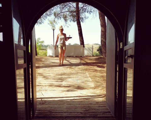 Donna che cammina con un vassoio attraverso porte aperte a Casa & Glamping Sorriso, parco vacanze in Umbria, Italia.