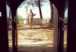 Donna che cammina con un vassoio attraverso porte aperte a Casa & Glamping Sorriso, parco vacanze in Umbria, Italia.