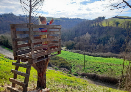 Een kind staat in een boomhut met uitzicht op het landschap bij Casa & Glamping Sorriso in Umbrië, Italië.