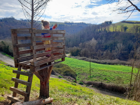Ein Kind steht in einem Baumhaus mit Blick auf Hügel bei Casa & Glamping Sorriso in Umbrien, Italien.