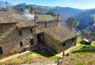Stenhus med tegltag i Umbria, Italien, omgivet af bakker og natur, set fra oven i klart solskin.